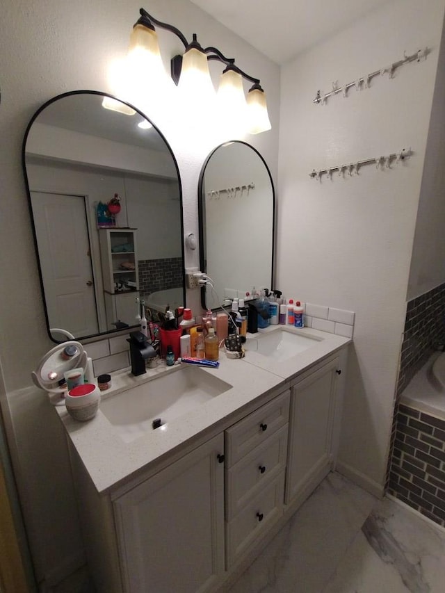 bathroom with double vanity, marble finish floor, a tub, and a sink