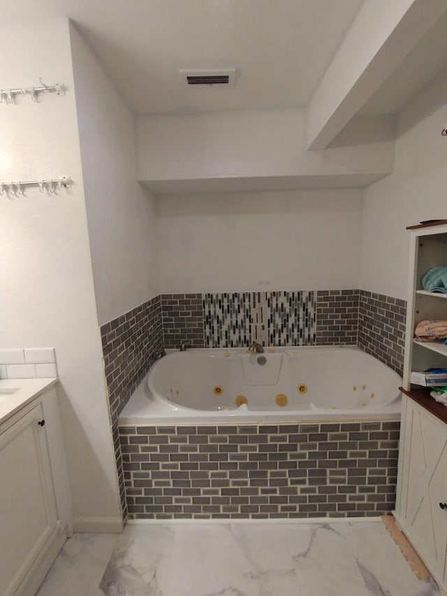 full bathroom with marble finish floor, visible vents, vanity, and a tub with jets