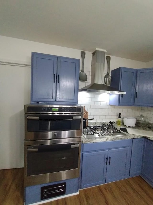 kitchen with blue cabinetry and wall chimney exhaust hood