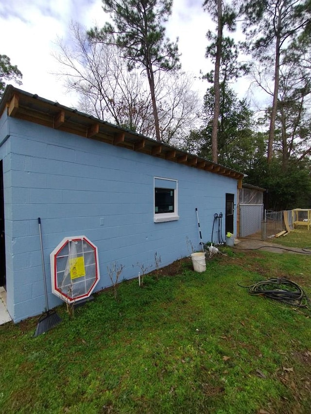 view of side of property with a lawn and concrete block siding