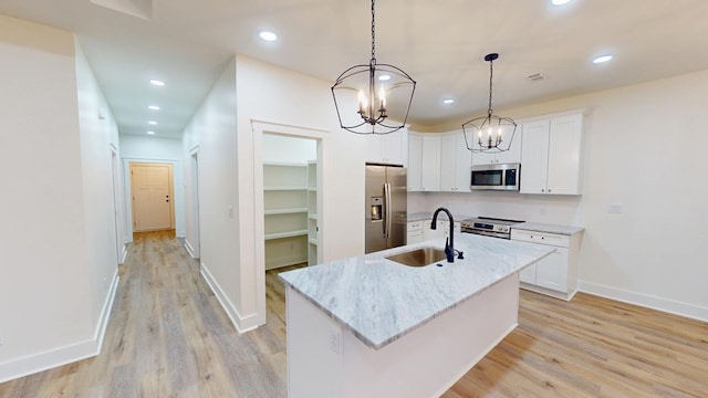 kitchen featuring an island with sink, hanging light fixtures, sink, appliances with stainless steel finishes, and white cabinets