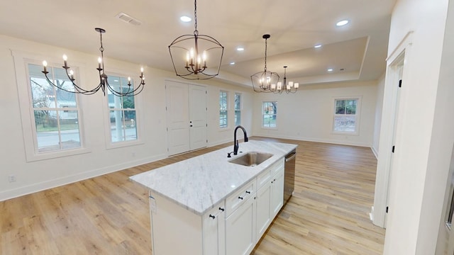 kitchen featuring a center island with sink, hanging light fixtures, dishwasher, sink, and white cabinetry