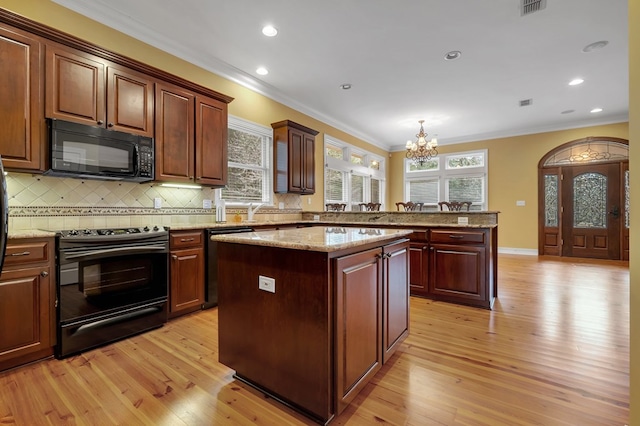 kitchen featuring pendant lighting, crown molding, a center island, tasteful backsplash, and black appliances