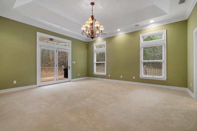 spare room with an inviting chandelier, ornamental molding, a raised ceiling, and light carpet