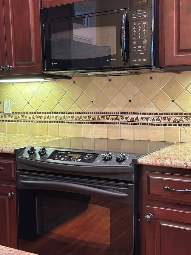 kitchen featuring light stone countertops, decorative backsplash, and black appliances