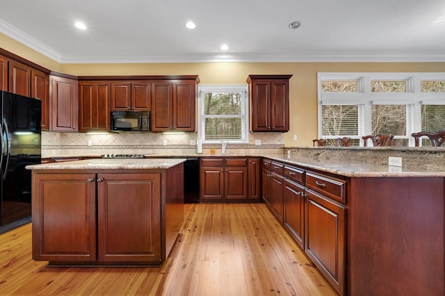 kitchen featuring tasteful backsplash, crown molding, light stone counters, and black appliances