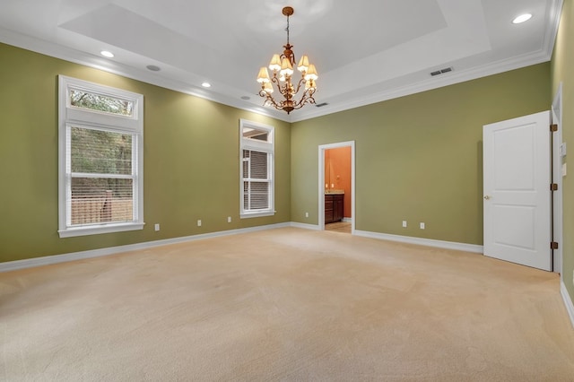 empty room with light carpet, a tray ceiling, and crown molding