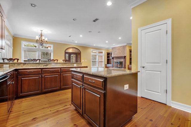 kitchen with a kitchen island, a notable chandelier, light stone counters, crown molding, and light hardwood / wood-style flooring