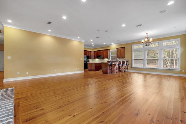 living room featuring a notable chandelier, ornamental molding, and light wood-type flooring