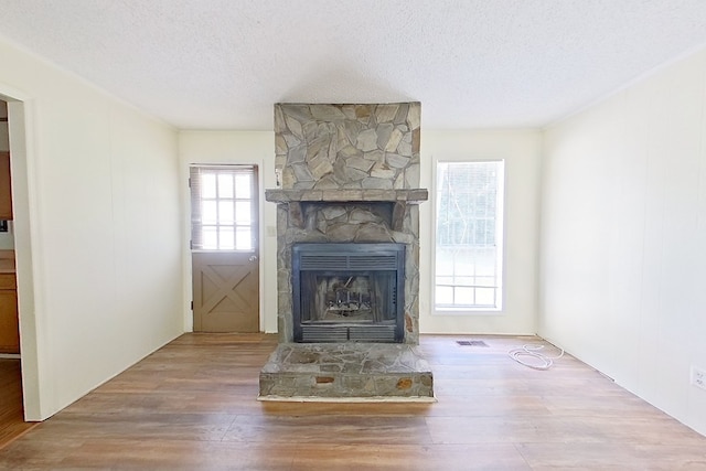 452 Bn Railroad Cir, Boston, GA 31626 - unfurnished living room with a stone fireplace, wood finished floors, and a textured ceiling