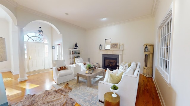 living room with crown molding, wood-type flooring, and decorative columns