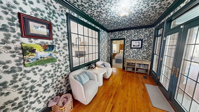 sitting room with crown molding, wood-type flooring, and french doors