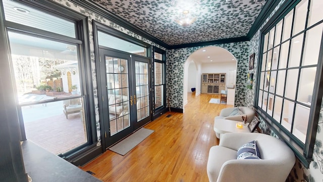 interior space with crown molding, wood-type flooring, a wealth of natural light, and french doors