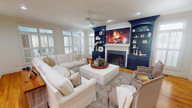 living room featuring ornamental molding, plenty of natural light, ceiling fan, and light wood-type flooring