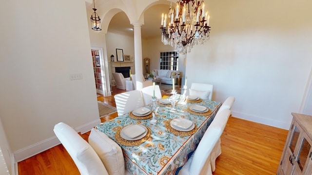 dining room with decorative columns, crown molding, a notable chandelier, and light hardwood / wood-style flooring