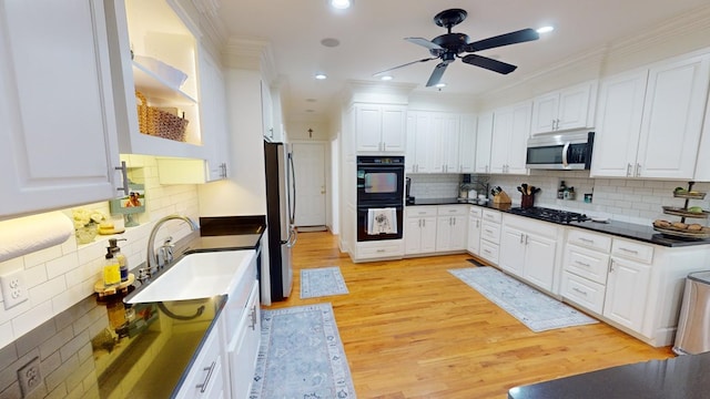 kitchen featuring sink, tasteful backsplash, black appliances, light hardwood / wood-style floors, and white cabinets