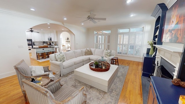 living room with ceiling fan, ornamental molding, and light hardwood / wood-style flooring