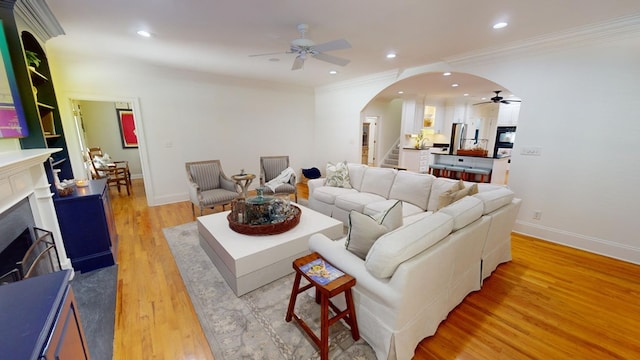 living room with ornamental molding, light hardwood / wood-style floors, and ceiling fan