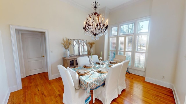 dining area featuring ornamental molding, light hardwood / wood-style floors, and a notable chandelier