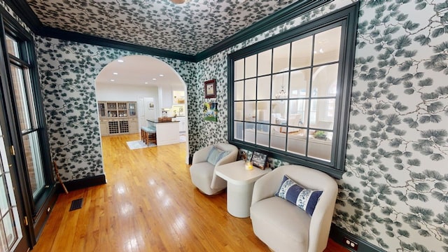 living area with ornamental molding and light wood-type flooring