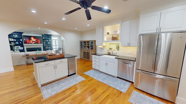 kitchen featuring sink, white cabinets, decorative backsplash, stainless steel appliances, and light wood-type flooring