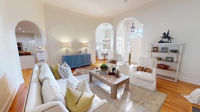 living room with crown molding, a chandelier, and light hardwood / wood-style floors