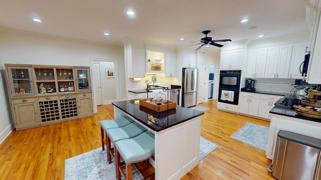 kitchen with a kitchen bar, white cabinetry, light hardwood / wood-style flooring, a kitchen island, and stainless steel appliances