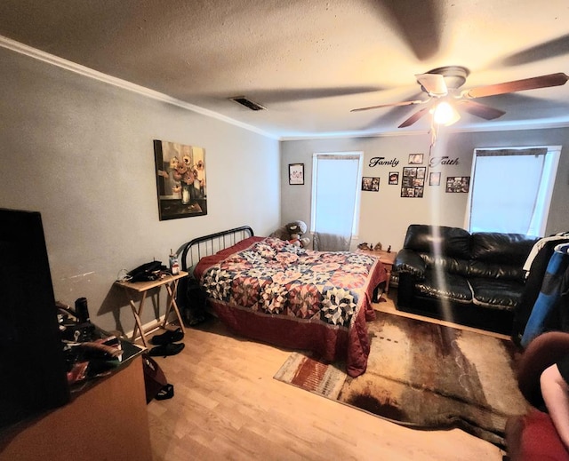 bedroom with hardwood / wood-style flooring, ceiling fan, ornamental molding, and a textured ceiling