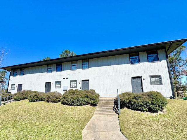 view of property featuring stairway and a front yard