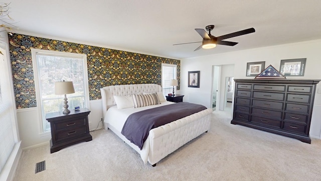 bedroom featuring visible vents, light colored carpet, ceiling fan, and multiple windows