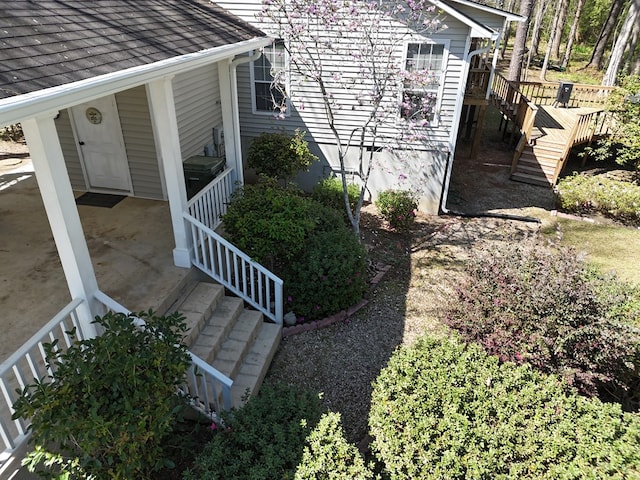 view of property exterior featuring a shingled roof and stairs