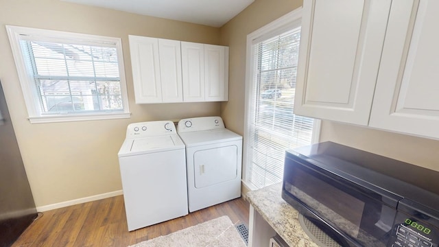 laundry area with cabinet space, wood finished floors, independent washer and dryer, and baseboards