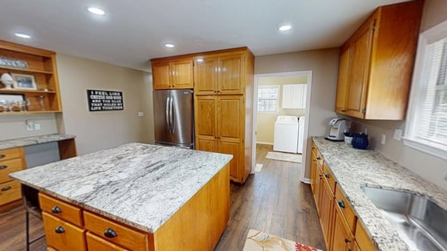 kitchen with a sink, dark wood finished floors, a center island, freestanding refrigerator, and a healthy amount of sunlight