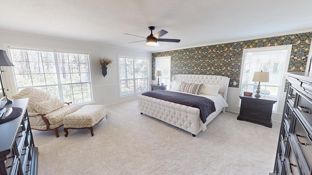 bedroom featuring a ceiling fan, light colored carpet, crown molding, and wallpapered walls