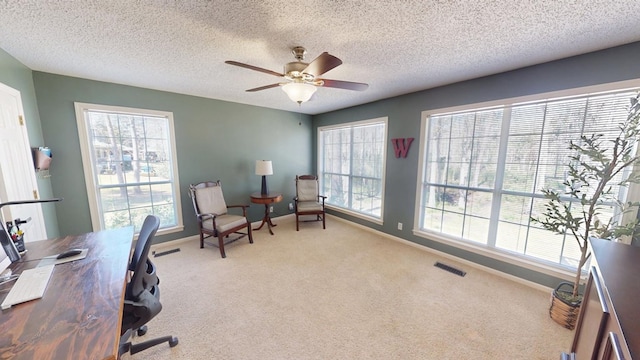 carpeted office with a wealth of natural light, visible vents, baseboards, and ceiling fan