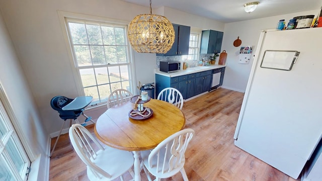 dining room with a chandelier, light wood-style flooring, and baseboards