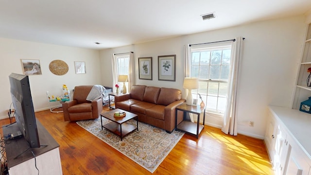 living room with light wood-style floors, baseboards, and visible vents