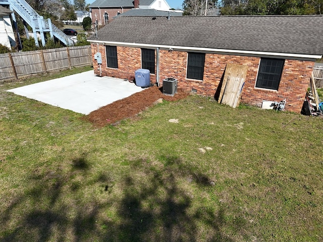 rear view of house with a yard, brick siding, a patio area, and fence