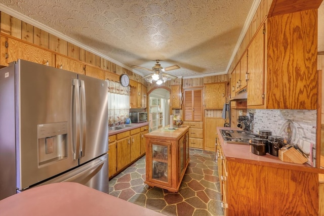 kitchen featuring crown molding, appliances with stainless steel finishes, wooden walls, and a center island