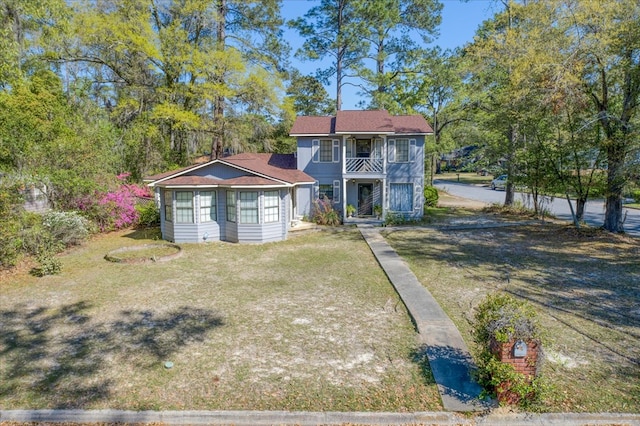 view of front of house featuring a front yard and a balcony