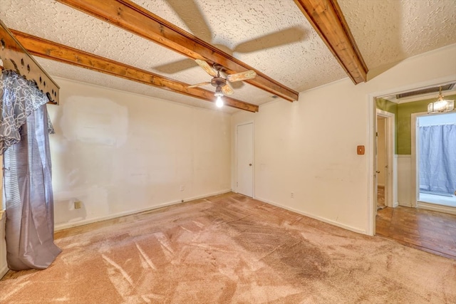 carpeted empty room featuring ceiling fan, a textured ceiling, and beamed ceiling