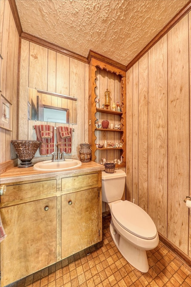 bathroom with crown molding, vanity, toilet, and wood walls