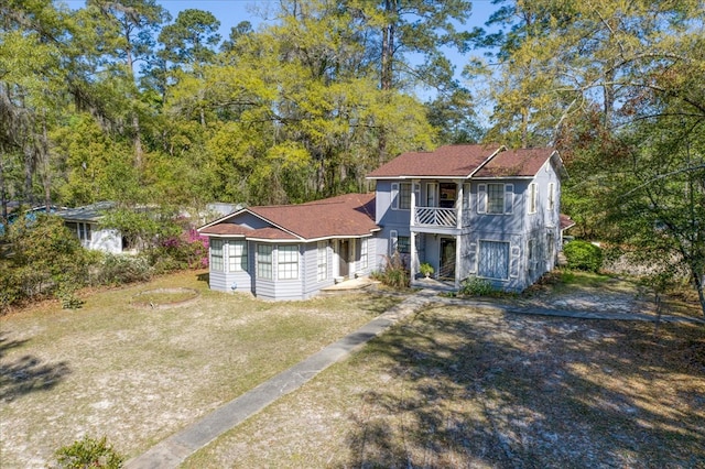 view of front of home featuring a balcony and a front lawn