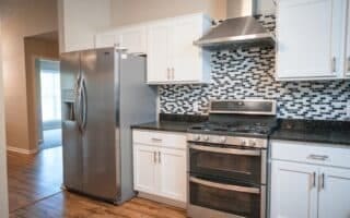 kitchen featuring white cabinetry, stainless steel appliances, extractor fan, and decorative backsplash