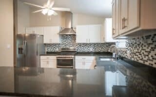 kitchen featuring sink, range hood, stainless steel refrigerator with ice dispenser, tasteful backsplash, and white cabinets