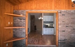 kitchen with brick wall, wood-type flooring, lofted ceiling, and wooden walls