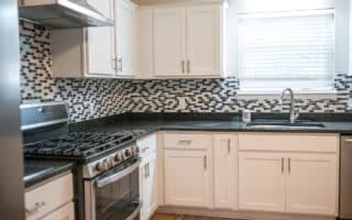 kitchen featuring stainless steel gas stove, sink, decorative backsplash, and white cabinets