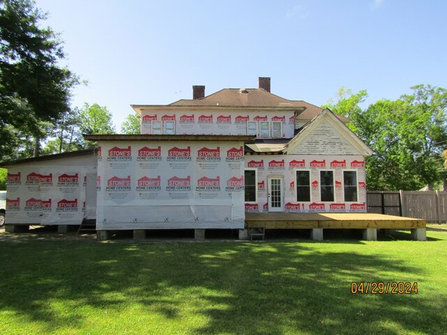 rear view of property featuring a deck and a lawn