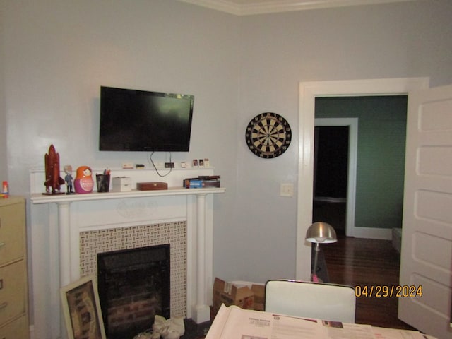 living room featuring a tiled fireplace, crown molding, and wood-type flooring