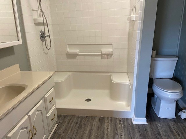 bathroom with wood-type flooring, toilet, vanity, and a shower